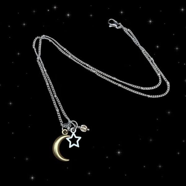 Moon and star necklace with crystal accent displayed on black starry background