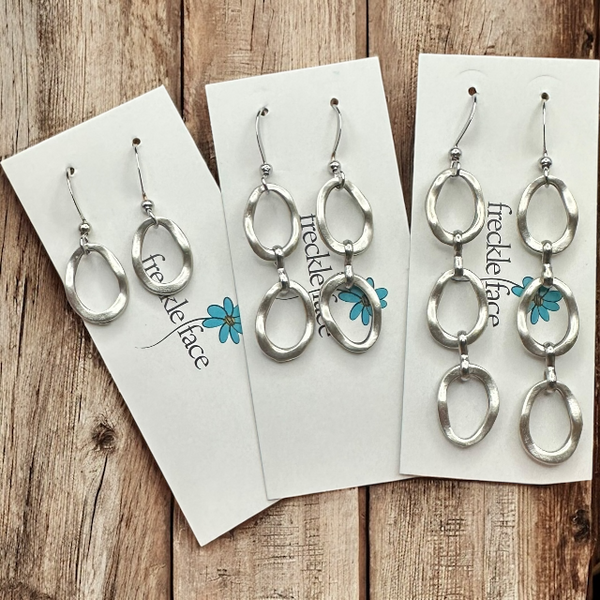 Mulitple options of Matte silver wavy hoop drop earrings on jewelry display card