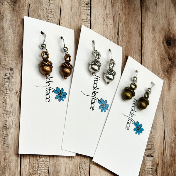 Mixed metal small acorn earrings laying on a wood table
