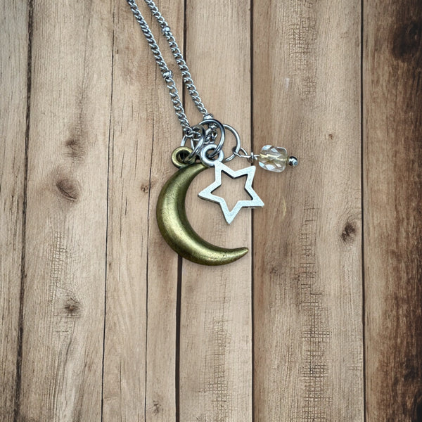 Close-up of moon and star charms with crystal bead on stainless steel necklace