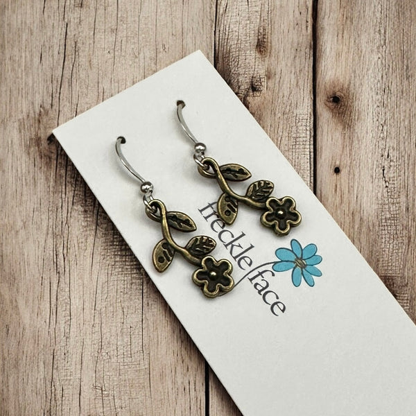 Bronze floral vine earrings displayed on Freckle Face Jewellery card with rustic wood backdrop.