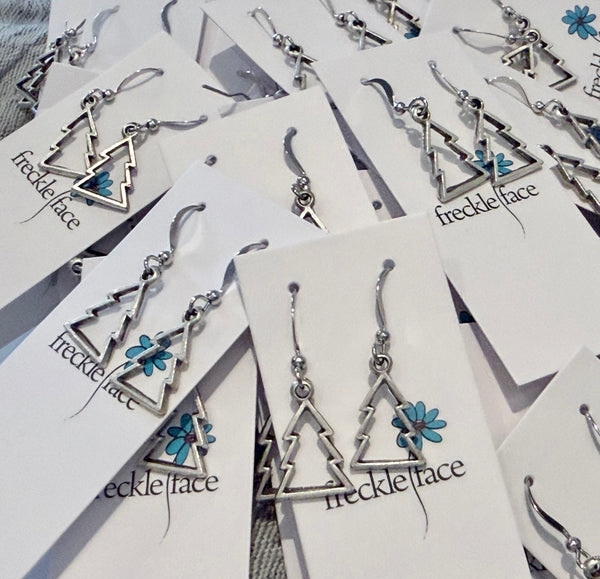 lots of christmas tree earrings in a pile