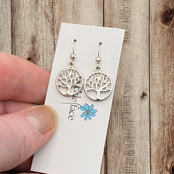 Tree silhouette dangle earrings in shiny rhodium silver displayed on brand card