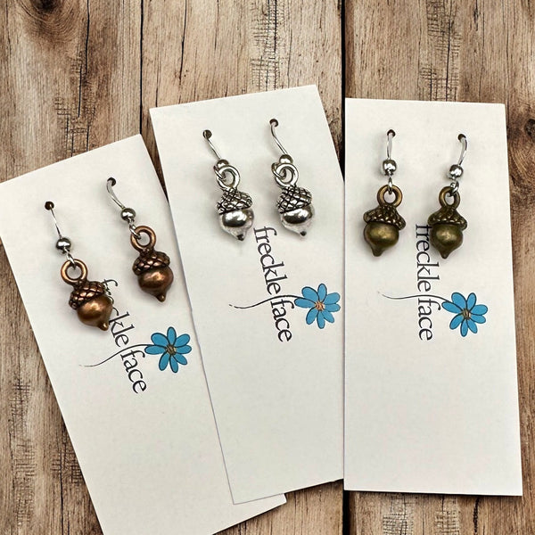 Simple acorn earrings with French hooks and silicone stoppers displayed flat