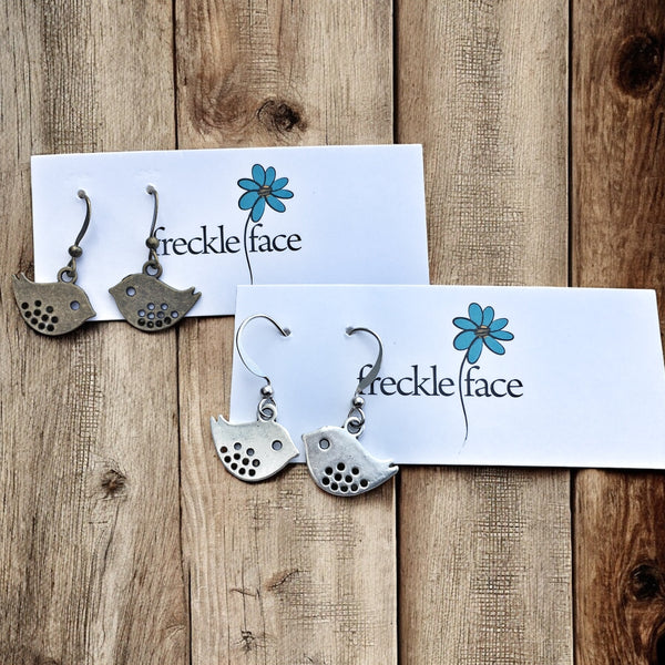 Bird silhouette hook earrings in silver and antique bras displayed on jewelry card