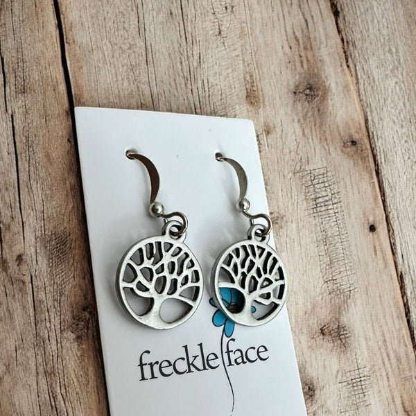 Matte silver tree of life earrings on rustic table
