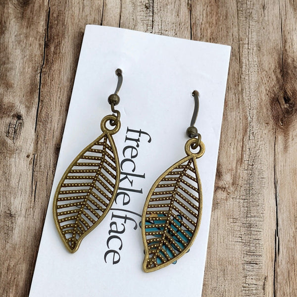 Nature inspired brass leaf earrings with silicone stoppers displayed on white background card