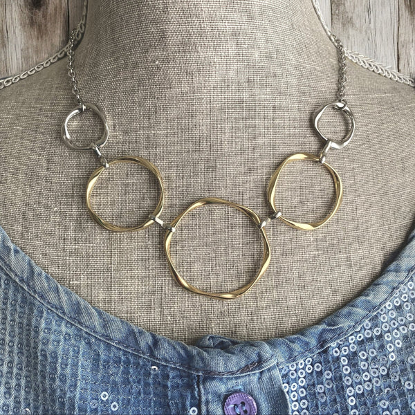 Mixed metal necklace on mannequin with gold and silver interlinked circles in statement design.