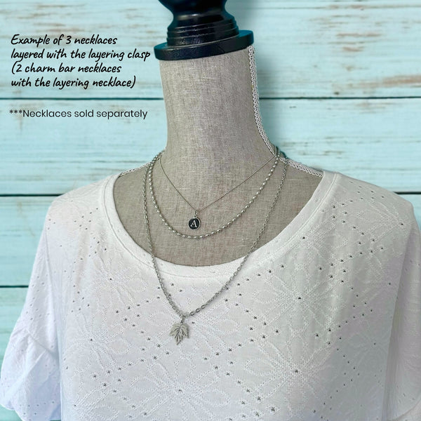 Mannequin wearing layered necklaces with a layering clasp against a light blue background.