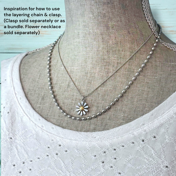 Mannequin wearing a layered necklace with a flower pendant on a light blue background