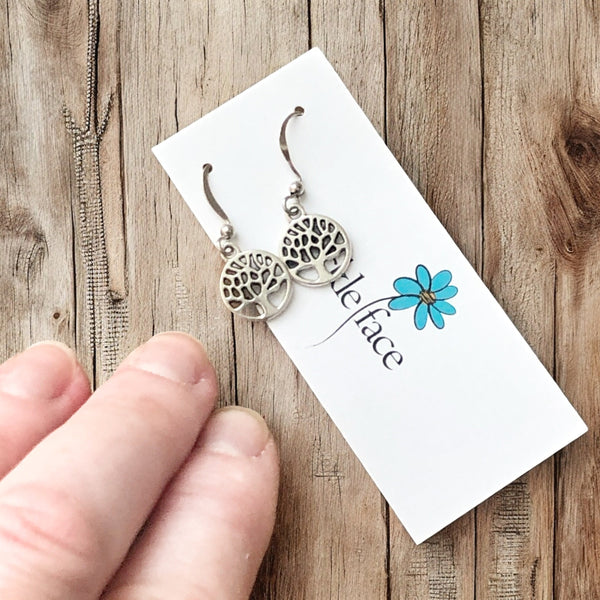 Nature-inspired tiny tree dangle earrings styled with wood background
