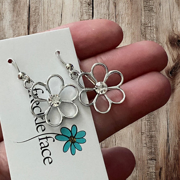 Close-up of silver five-petal floral charm with sparkling rhinestone for dainty earrings