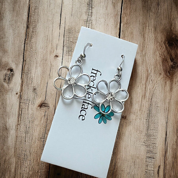 Metallic flower dangle earrings with rhinestone center on earring card