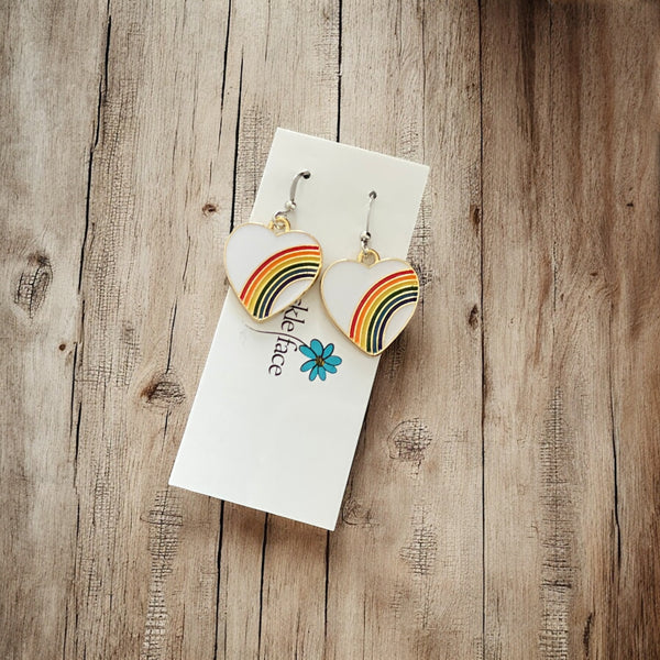 Bright rainbow heart earrings photographed against a wood  background