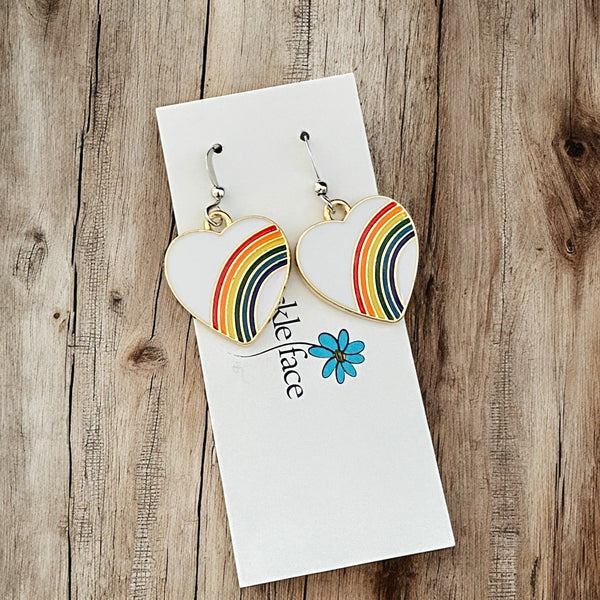 Rainbow heart hook earrings with white enamel and multicolor rainbow displayed on jewelry card