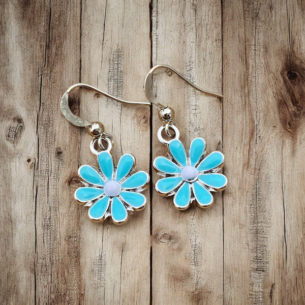 Blue enamel flower hook earrings with white center grainy wood table