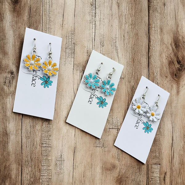 Colorful enamel daisy hook earrings with blue petals, yellow center, and white accents
