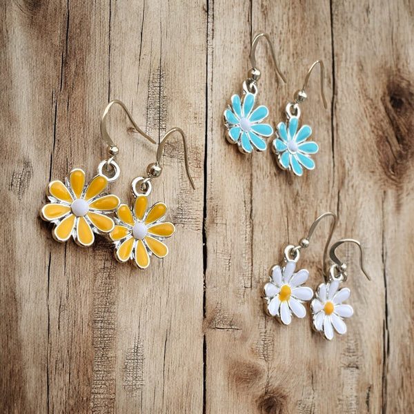 Colorful daisy hook earrings with enamel petals on hypoallergenic ear wires, displayed on a rustic wood background