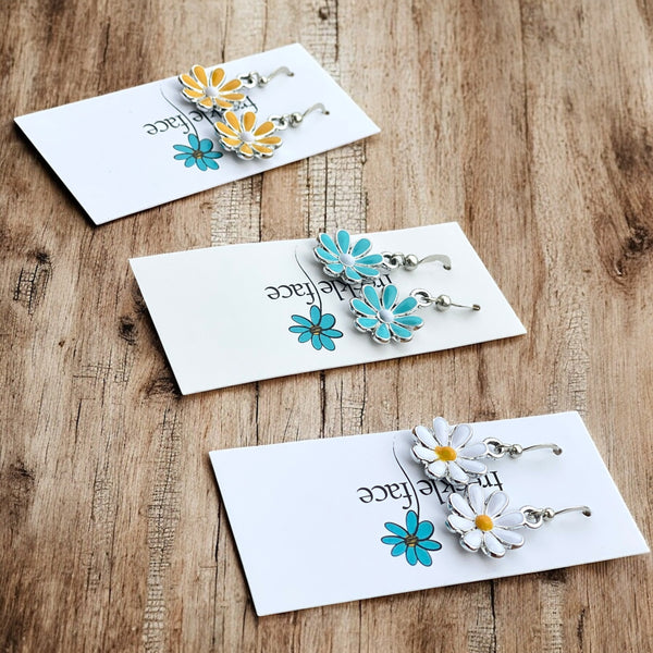 Glossy enamel flower earrings on freckle face brand card