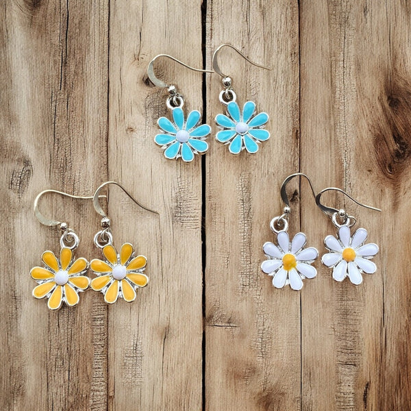 Enameled colorful Daisy earrings on ear sensitive hooks laid out on wood background