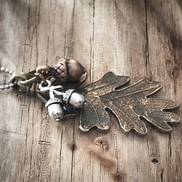Close up of antique brass oak leaf necklace with silver and antique copper small acorns dangling on the pendant
