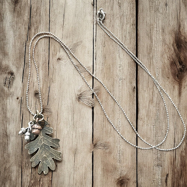 Boho-style bronze oak leaf & acorn necklace laid out on wood
