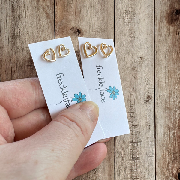 Close‑up of 8 mm and 12mm gold open heart stud earring with silicone back