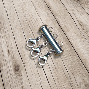 Stainless steel magnetic layering clasp with three lobster clasps on wood background