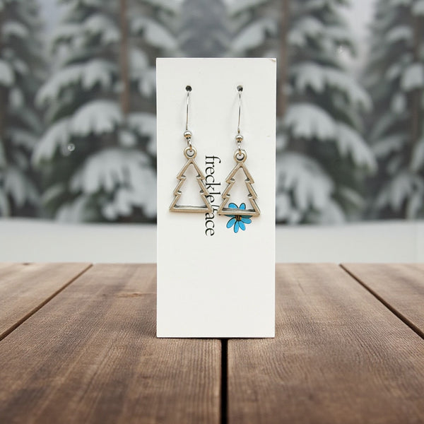 tree shapped earrings on a branded card with a blurred snowy background